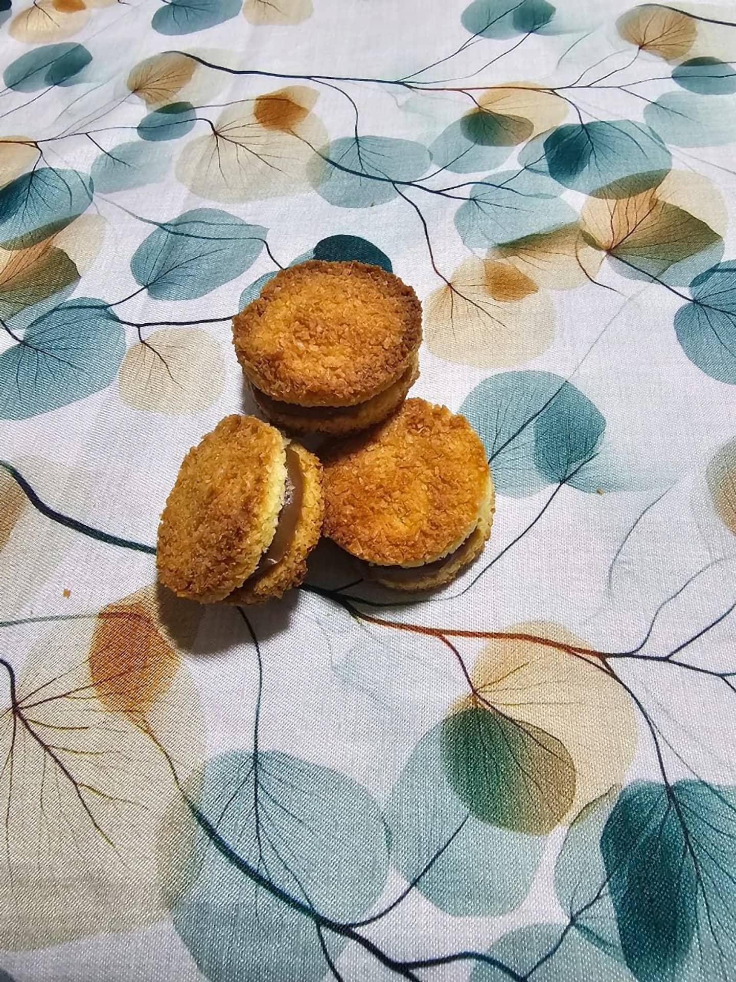 Tres alfajores de coco con relleno, sobre mantel de hojas